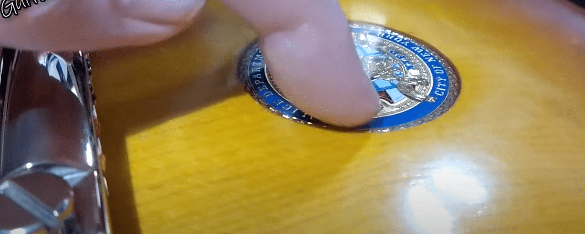 An NYPD challenge coin, embedded in a Les Paul guitar